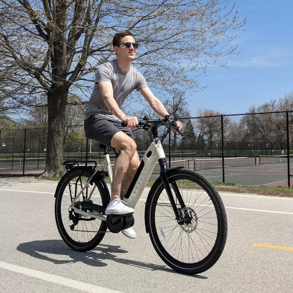 Photo of Viktor Köves on his White Gazelle ebike, riding down Chicago's Lakefront trail
          past a tennis court, wearing shorts, a t-shirt and sunglasses