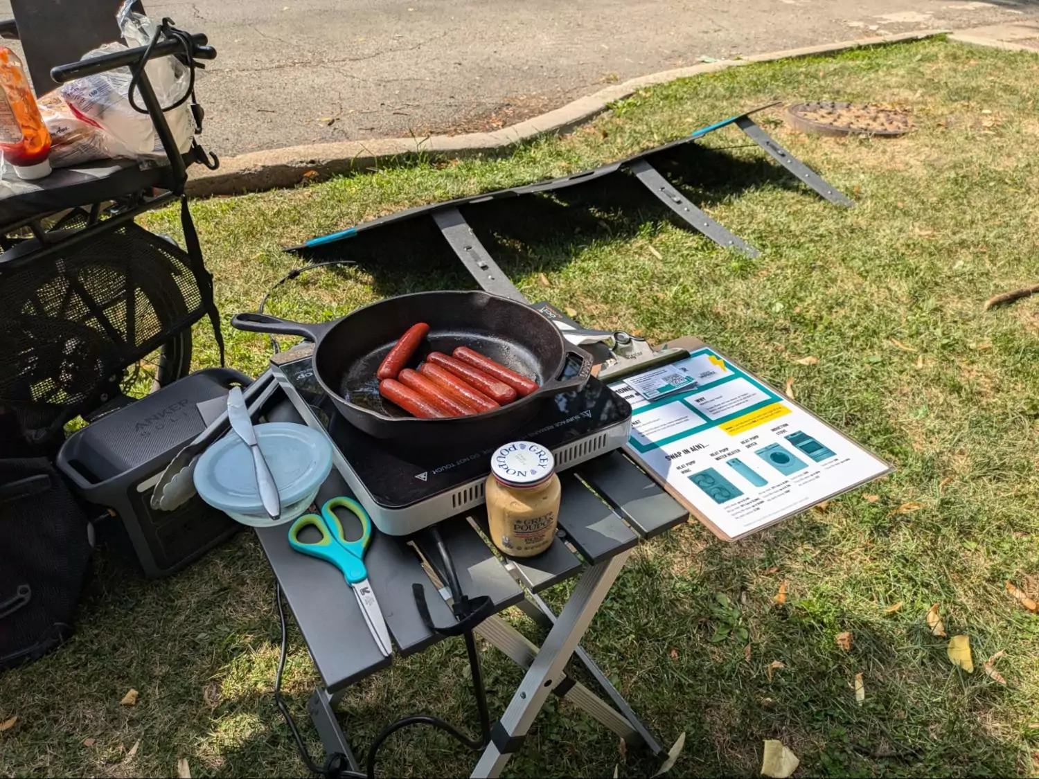 The solar and battery setup from the previous photo opened up, with hot dogs cooking
      on an induction cooktop.