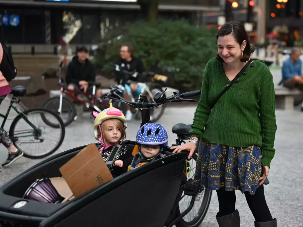 A mom smiling with her two kids in an Urban Arrow